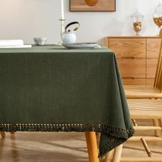 a green table cloth on top of a wooden chair with a tea pot and cup