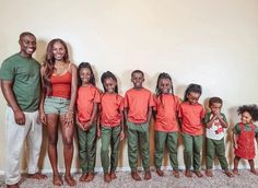 a group of people standing next to each other in front of a wall with an orange shirt and green pants