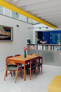 a dining room table and chairs in front of a book shelf with books on it