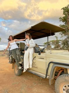 a man and woman sitting on the back of a safari vehicle with an awning