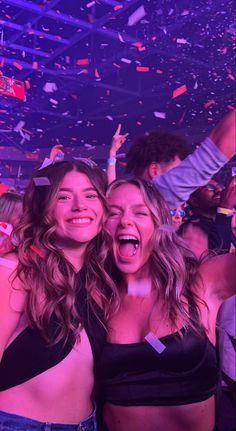 two women standing next to each other in front of confetti falling from the ceiling