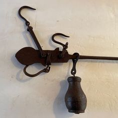 an old hook with a bell hanging from it's side on a white wall