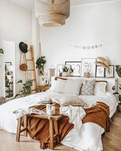 a bed with white sheets and pillows in a bedroom next to a wooden ladder filled with plants