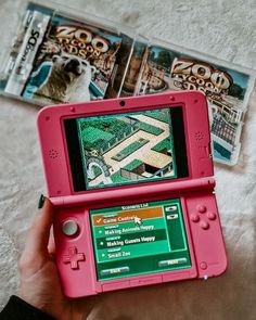 a pink nintendo wii game system sitting on top of a bed next to two games