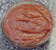 a glass bowl filled with sauce sitting on top of a counter