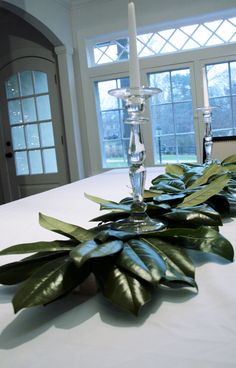 the table is set with silver candlesticks and green leaves