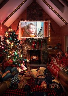 two people sitting on couches in front of a christmas tree with lights and a flat screen tv