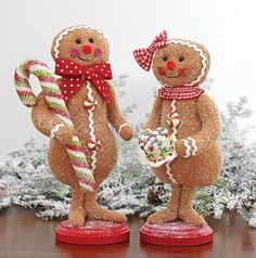 two gingerbread man standing next to each other holding candy canes in their hands