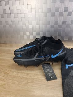 a pair of black and blue nike soccer cleats on a wooden floor next to a plaque