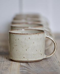 two white coffee cups sitting on top of a wooden table