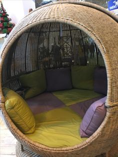 a bed made out of wicker with pillows on it and a bird cage in the background