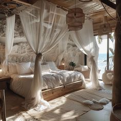 a bedroom with white bedding and curtains on the ceiling, along with an ocean view