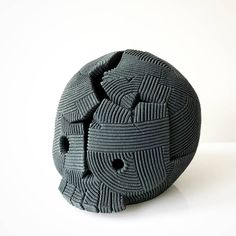 a black ball with holes in it sitting on a white surface