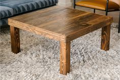 a wooden table sitting on top of a white carpeted floor next to a blue couch