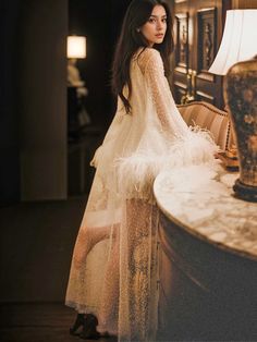 a woman standing in front of a table with a lamp on it