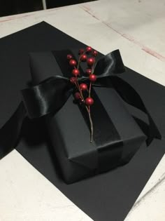 a black gift box with red berries tied around it