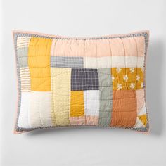 an orange and yellow patchwork pillow on a white wall