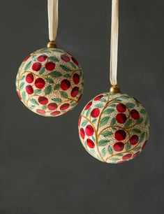 two ornaments hanging from strings on a gray background