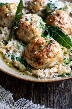 some meatballs and pasta on a plate with green leafy garnishes