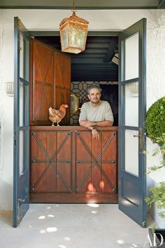 a man standing in an open doorway next to a chicken