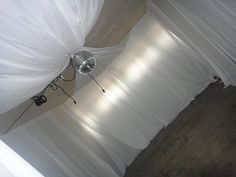 a room with white drapes covering the walls and ceiling, along with two lights on each side of the wall