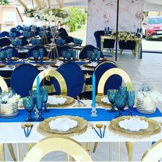 a table set up with blue and gold plates, napkins, and place settings