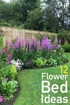 a garden filled with lots of flowers next to a wooden fence and lush green grass