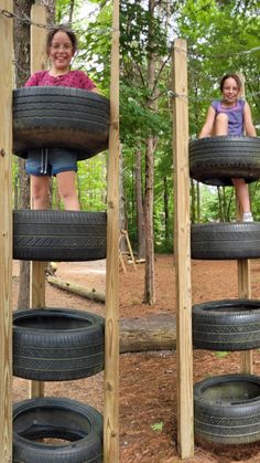 two girls are playing in a tire - rimed play structure made out of old tires