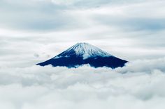 an image of a mountain in the sky with clouds around it that is blue and white