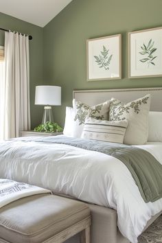 a bedroom with green walls and white bedding in the corner, along with two framed pictures on the wall