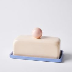 a white and blue cake with a single peach on it's top sitting on a plate