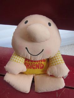 a stuffed pig sitting on top of a red table next to a white and yellow wall