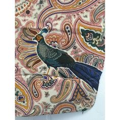 a bird is sitting on top of a paisley print purse