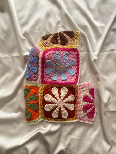 a crocheted purse is laying on a white sheet and has flowers in the center