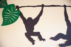 two people hanging upside down on a rope with leaves in the backgrouds