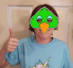 a person wearing a green bird mask with a unicorn on it's face and thumbs up