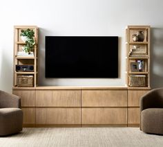 a living room with two chairs and a flat screen tv mounted on a wooden entertainment center