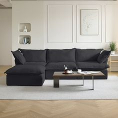 a living room with a black couch and coffee table in front of white wall art