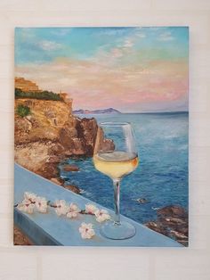 a painting of a glass of white wine on a balcony overlooking the ocean and cliffs