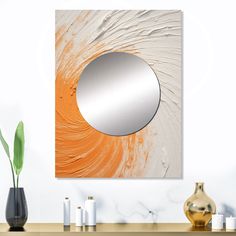 an orange and white painting with a round mirror on the wall next to some vases