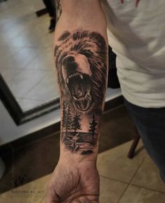 a man's arm with a bear tattoo on it and trees in the background