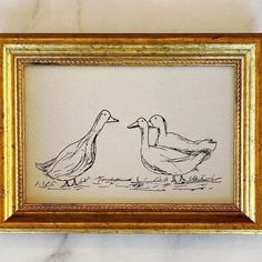 a drawing of two ducks standing next to each other in a gold frame on a wall