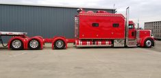 a large red semi truck parked in front of a building with a trailer attached to it