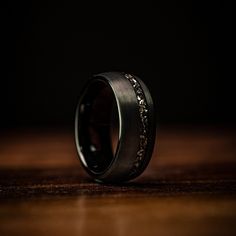 a wedding band with an intricate design is shown on a wooden table in the dark