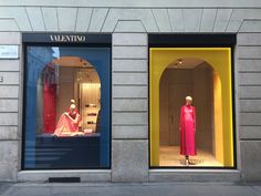 two windows with mannequins dressed in pink and yellow, on the sidewalk