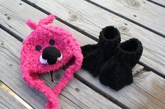 two crocheted slippers and a stuffed animal on a wooden bench with wood planks