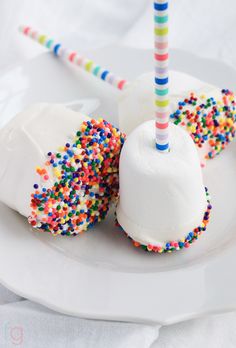 two ice creams with sprinkles and a candle on a white plate