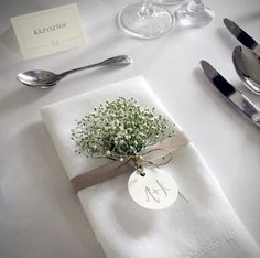 a place setting with napkins, silverware and baby's breath flower arrangement