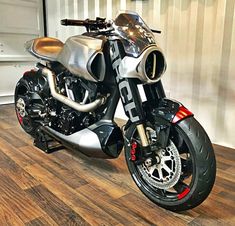 a silver motorcycle parked on top of a wooden floor next to a white wall and door