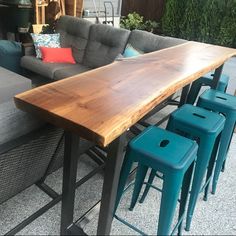 a wooden table sitting on top of a patio next to blue stools and couches